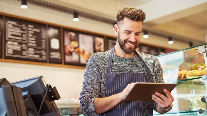 A shop assistant checking a tablet behind the counter during the shift